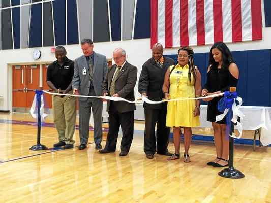 Six representatives of Lorain voters and students cut a silver ribbon with golden scissors Sept. 16, 2016, in a gymnasium at a new Lorain High School, 2600 Ashland Ave., Lorain. From left: Mark Ballard, member of Lorain City School Board; Dr. Jeff Graham, superintendent of Lorain City Schools; Bill Sturgill, member of Lorain School Board; Tim Williams, president of Lorain School Board; Pam Carter, Ward 3 on Lorain City Council; and Tatum Hall, 14, a freshman at Lorain High School who participated in the groundbreaking ceremony for the building. (Photo by Carol Harper — The Morning Journal)